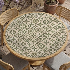 May include: A round wooden table featuring a tabletop with a repeating green and white geometric tile pattern. The table is surrounded by four wooden chairs with woven cane backrests and light gray upholstered seats.