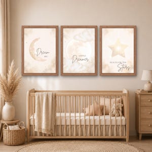 Könnte beinhalten: Drei gerahmte Wandbilder mit einer Mondsichel, einem Vollmond und einem Stern mit Wolken in Beige- und Cremetönen. Die Drucke enthalten die Texte Dream Big, Little Dreamer und Reach for the Stars in einer dunklen Schreibschrift.