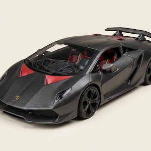 May include: A matte black scale model of a Lamborghini Sesto Elemento sports car featuring red interior accents, a rear spoiler, black wheels, and the iconic yellow and black Lamborghini emblem on the front hood of the vehicle.