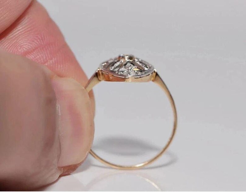 Peut inclure: Une bague en or dot&eacute;e d'une t&ecirc;te de forme ovale avec une surface sup&eacute;rieure argent&eacute;e sertie de multiples petites pierres claires &agrave; facettes. L'anneau est fin et circulaire, fabriqu&eacute; en or jaune poli, reli&eacute; au sertissage orn&eacute; de pierres.
