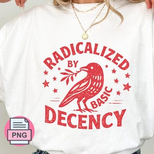 May include: A white crewneck t-shirt featuring a red graphic print of a bird holding a branch, surrounded by small stars. The text reads "RADICALIZED BY BASIC DECENCY" in a distressed, bold red font. The design is centered on the chest.