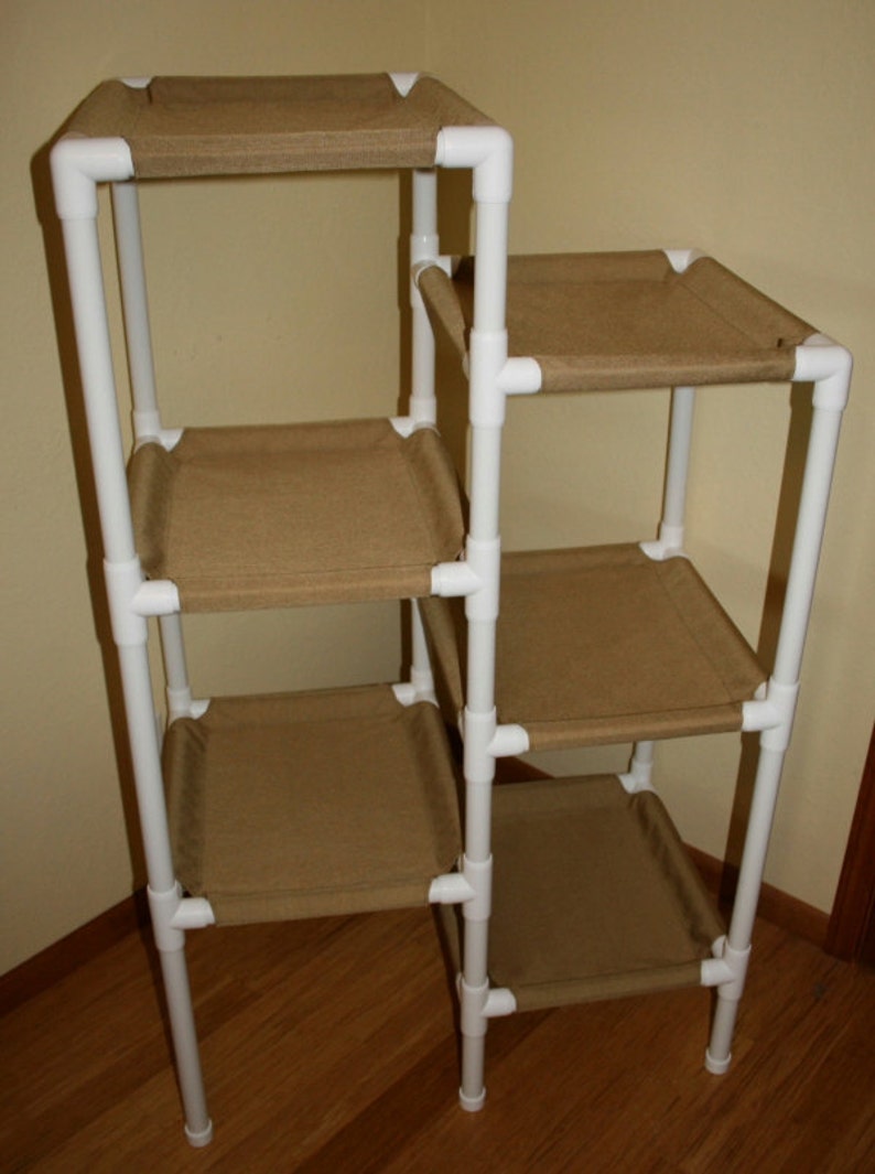 May include: A white PVC pipe cat tree with five platforms covered in brown fabric. The cat tree is freestanding and has a simple design.