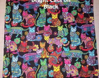 May include: A black fabric with a repeating pattern of colorful cats with intricate designs. The text "Bright Cats on Black" is printed at the top of the fabric.