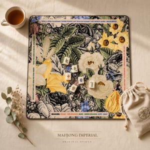 Puede incluir: Un tapete de mahjong cuadrado con un estampado bot&aacute;nico detallado de narcisos amarillos, rosas blancas y follaje verde. El tapete incluye instrucciones y reglas de juego impresas en los bordes, con cinco fichas de mahjong en el centro.