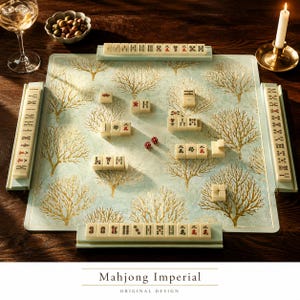 May include: A Mahjong game set featuring a square board with a light blue background and gold tree patterns. The set includes ivory-colored tiles with black and red characters, four tile racks, and two red dice. Text reads Mahjong Imperial.
