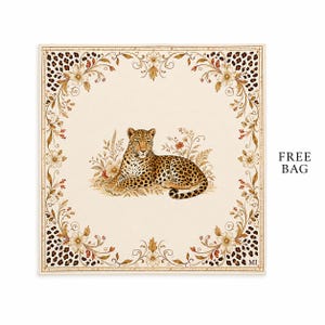 Puede incluir: Un pañuelo cuadrado con una ilustración central de un leopardo descansando entre flores. El borde muestra un patrón de enredaderas florales y manchas de leopardo sobre un fondo crema. Las letras MI están impresas en la esquina inferior derecha.