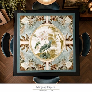 May include: A square table mat featuring a central circular medallion with a lotus flower and palm leaves, surrounded by a Greek key border. The background displays a tropical botanical pattern in shades of sage green, gold, and cream.