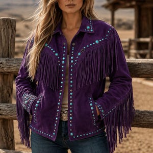 May include: A deep purple suede jacket featuring long fringe detailing along the chest and sleeves. The jacket is adorned with silver-toned studs and circular turquoise-colored accents lining the front placket, collar, and sleeve cuffs.