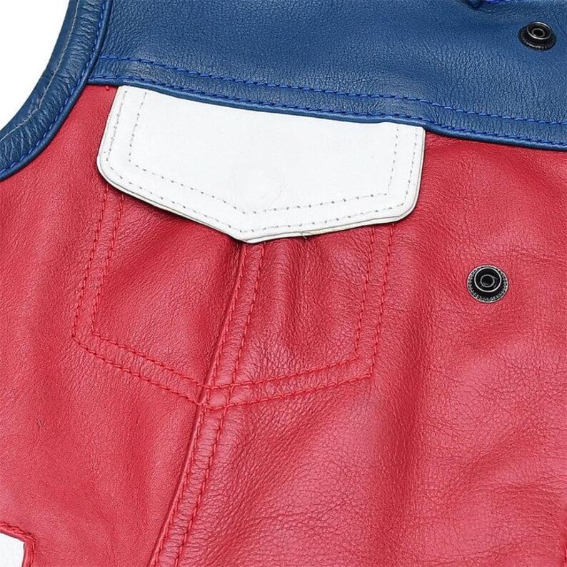 Puede incluir: Un chaleco de cuero con cuerpo rojo, bolsillo con solapa blanco y secci&oacute;n superior azul. La prenda incluye botones de presi&oacute;n de metal negro en el &aacute;rea del hombro azul y en el panel frontal rojo, con costuras visibles en el bolsillo.