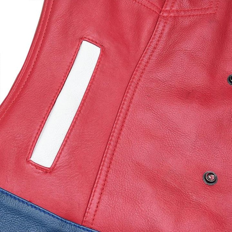 Puede incluir: Una chaqueta de cuero roja con una abertura de bolsillo rectangular blanca vertical, costuras dobles visibles y un bot&oacute;n de presi&oacute;n de metal oscuro. La parte inferior de la prenda cambia a una secci&oacute;n de cuero azul texturizado en el borde.