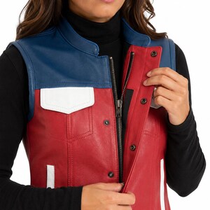 Puede incluir: Un chaleco sin mangas de cuero en colores rojo, azul y blanco. La prenda presenta un panel superior azul en el pecho, un cuerpo principal rojo y solapas de bolsillo blancas. Incluye un cierre de cremallera central con una tapeta de botones a presi&oacute;n.