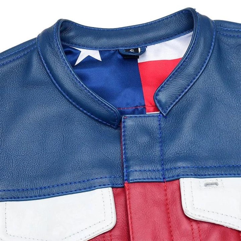 Puede incluir: Una chaqueta de cuero azul, roja y blanca con cuello mao y cierre frontal. El forro interior muestra un patr&oacute;n estampado de una estrella blanca sobre un campo azul junto a rayas rojas y blancas, visible en la l&iacute;nea del cuello.