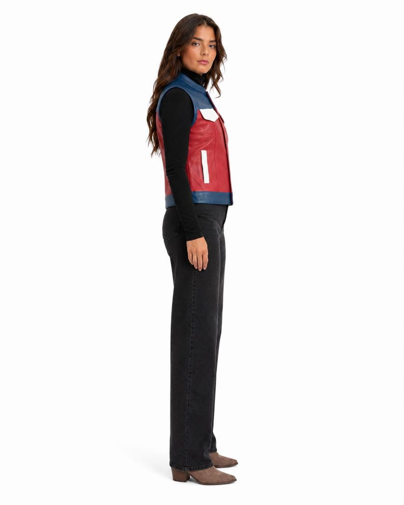 Puede incluir: Un chaleco sin mangas con cuerpo rojo, ribetes azules en hombros y dobladillo, y solapas de bolsillo blancas. El chaleco se lleva sobre una camiseta negra de manga larga y pantalones negros, con botines marrones, visto desde un perfil lateral.