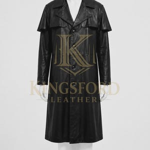 May include: A black leather trench coat featuring a wide collar, a button-down front closure, and a cape-style overlay across the shoulders. The garment displays the text Kingsford Leather in a gold font centered on the front of the coat.