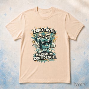 May include: An ivory short-sleeved t-shirt featuring a graphic of a teal gift box wearing sunglasses and shoes. The gift box is pointing and giving a thumbs up. The text reads ZERO TASTE. MAXIMUM CONFIDENCE. surrounded by star and burst shapes.