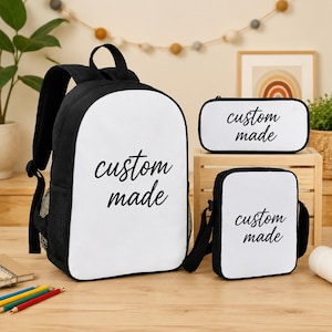 Könnte beinhalten: Ein schwarz-weißer Rucksack, ein rechteckiges Federmäppchen und eine kleine Umhängetasche, jeweils mit dem Text custom made in schwarzer Schreibschrift auf weißem Grund. Der Rucksack verfügt über seitliche Netztaschen und verstellbare Träger.