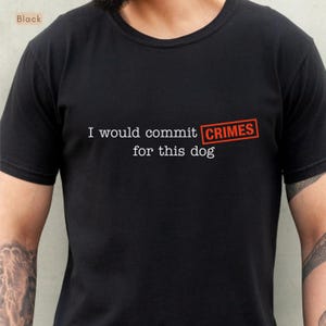 Könnte beinhalten: Ein schwarzes T-Shirt mit kurzen Ärmeln, das den weißen Text "I would commit" gefolgt von dem Wort "CRIMES" in einem roten, stempelartigen Rechteck zeigt, mit dem weißen Text "for this dog" in der Zeile unter dem roten Kasten.