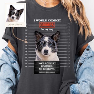 May include: A charcoal gray t-shirt featuring a mugshot-style graphic of a blue-eyed dog. The text reads I WOULD COMMIT CRIMES for my dog, LOVE. LOYALTY. ZOOMIES. NO REGRETS. CASE NO. 2026-BRUNO, alongside a height chart and a custom photo insert box.
