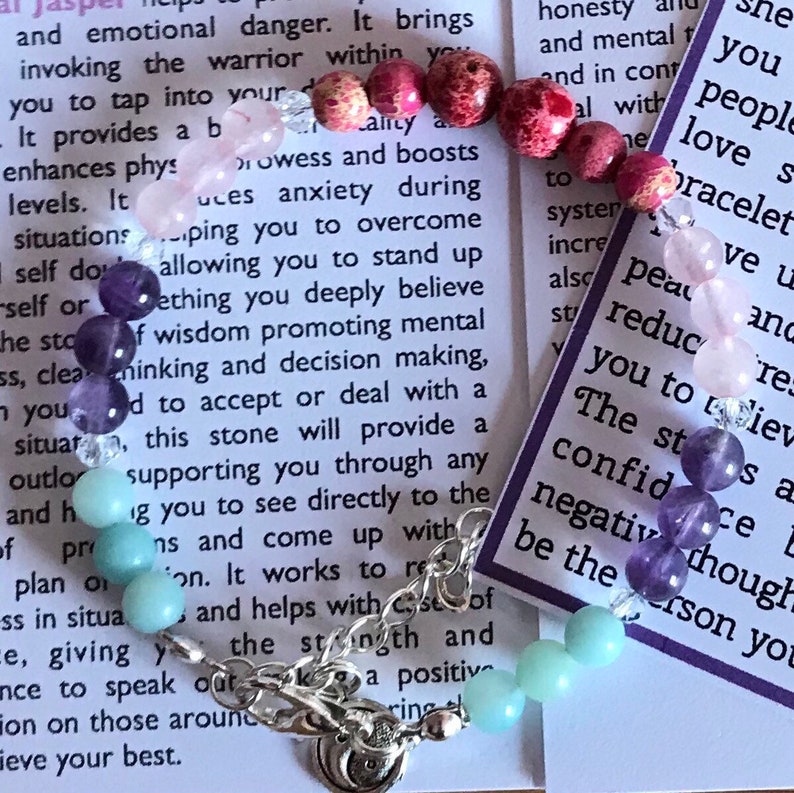 May include: A bracelet made with various colored stones, including amethyst, rose quartz, and aquamarine. The bracelet is on a white background with text about the stones' properties. The text reads: "honesty and mental... peace... reduce... The st... confid... negative though... be the person you..."