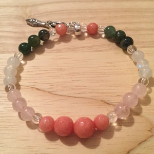 May include: A multi-colored beaded bracelet with a silver clasp. The bracelet features green, light blue, pink, and clear beads.