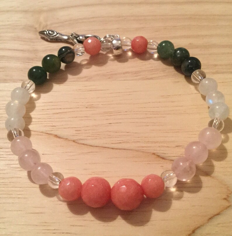 May include: A multi-colored beaded bracelet with a silver clasp. The bracelet features green, light blue, pink, and clear beads.