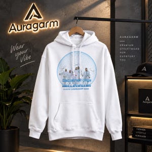 Puede incluir: Una sudadera con capucha blanca que presenta un estampado gráfico de los Backstreet Boys dentro de un globo terráqueo de alambre azul. El texto dice Backstreet Boys Millennium Live in Cobelsdorp 2025. La sudadera tiene mangas largas y bolsillo frontal.