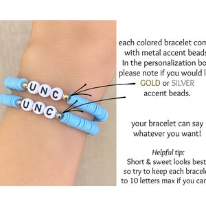 Puede incluir: Dos pulseras de cuentas azul claro con las letras "UNC" deletreadas en cuentas de letras blancas. Las pulseras tienen cuentas de acento doradas y plateadas. Las pulseras son un accesorio personalizado.
