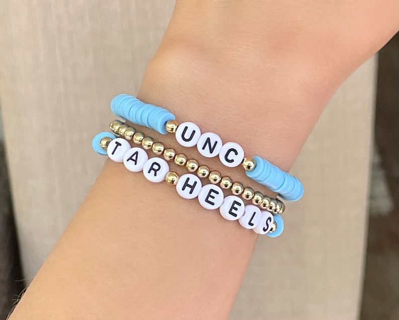 Puede incluir: Tres pulseras de cuentas. Una pulsera tiene cuentas de disco azul claro y las letras "UNC". Otra pulsera tiene las letras "TAR HEELS". La tercera pulsera est&aacute; hecha de peque&ntilde;as cuentas doradas.