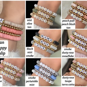 May include: A collection of colorful beaded bracelets with different names spelled out on them. The bracelets are made with small, round beads in various colors, including pink, tan, black, white, and gray. The names on the bracelets include "Mama", "Ellie", "Ava", "Avery", "Brooks", "Kenzie", "Cason", "Luver", "Vera", "Rowan", and "Sutty".