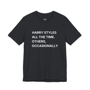 以下が含まれることがあります： 胸元に「HARRY STYLES ALL THE TIME. OTHERS, OCCASIONALLY.」という白いテキストがプリントされた黒の半袖Tシャツ。クルーネックで標準的なフィット感があり、襟の内側には小さなブランドラベルが見えます。