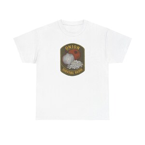 Puede incluir: Una camiseta blanca de manga corta con un parche gráfico centrado con borde verde oliva. El diseño muestra una cebolla roja, una cebolla blanca y trozos de cebolla picada con el texto ONION SURVIVAL BADGE en letras amarillas.