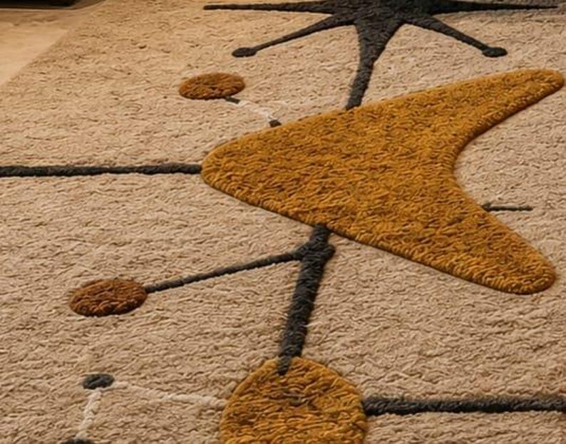 May include: A textured area rug featuring a beige background with a repeating pattern of dark gray lines, mustard yellow boomerang shapes, and small circular accents in both mustard yellow and dark gray, creating a geometric, mid-century inspired design.