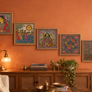 May include: Five square wall art pieces featuring intricate, colorful folk-style illustrations of figures, deities, and nature motifs. Each framed print displays detailed patterns in vibrant hues of red, blue, yellow, and green, arranged in a stepped formation.