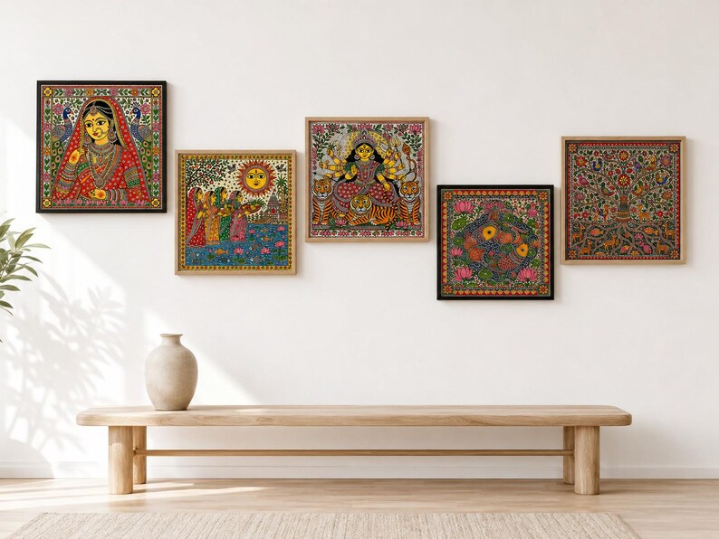 May include: A set of five square framed wall art pieces featuring intricate, colorful Indian folk art illustrations. The prints depict a woman in traditional attire, a sun scene with figures, a multi-armed deity on a tiger, a floral motif, and a tree.