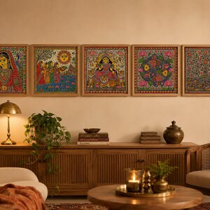 May include: Five square wall art pieces in light wood frames featuring intricate, colorful paintings. The artworks depict a person in traditional attire, a group near a sun, a multi-armed figure with tigers, fish among lotus flowers, and a tree.