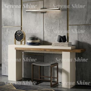 May include: A white console table with a natural wood accent strip, featuring a black and gold analog clock, a stack of bowls, and two books titled Architectural Forms and Geometric Forms. A dark gray stool sits below the table.