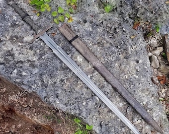 May include: A steel sword with a long, double-edged blade, a crossguard, and a wrapped grip, accompanied by a matching dark wooden scabbard. The word Anglesword is repeated across the image. The sword features a central fuller groove.