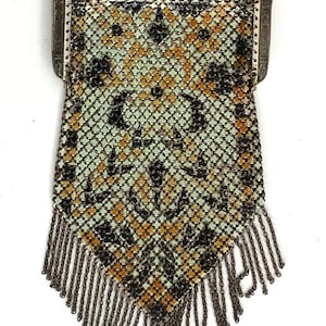 Peut inclure: Un sac &agrave; main en m&eacute;tal argent&eacute; ancien avec un cadre d&eacute;coratif et une cha&icirc;ne. Le maillage pr&eacute;sente un motif de carr&eacute;s noirs, dor&eacute;s et verts. Le bord inf&eacute;rieur est orn&eacute; d'une frange de cha&icirc;nes m&eacute;talliques pendantes.