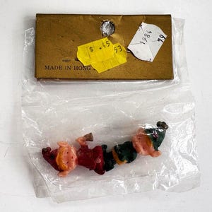 May include: A package containing small, vintage gnome figurines. The gnomes are in a clear plastic bag, with a cardboard header that reads "MADE IN HONG". The gnomes are wearing red, green, and tan clothing.