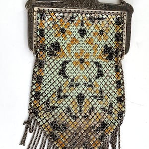 Peut inclure: Sac &agrave; main vintage en maille argent&eacute;e avec une cha&icirc;ne et des franges. Le sac pr&eacute;sente un motif g&eacute;om&eacute;trique noir, dor&eacute; et vert p&acirc;le. Le fermoir est orn&eacute; et la cha&icirc;ne est argent&eacute;e.