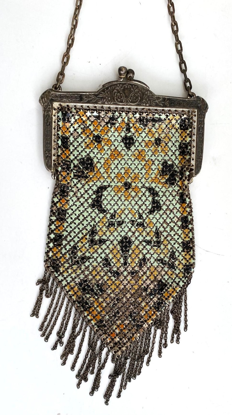 Peut inclure: Sac &agrave; main vintage en maille argent&eacute;e avec une cha&icirc;ne et des franges. Le sac pr&eacute;sente un motif g&eacute;om&eacute;trique noir, dor&eacute; et vert p&acirc;le. Le fermoir est orn&eacute; et la cha&icirc;ne est argent&eacute;e.