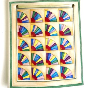 May include: A ceramic wall hanging with a green border and a pattern of 18 colorful sunbursts in a grid.