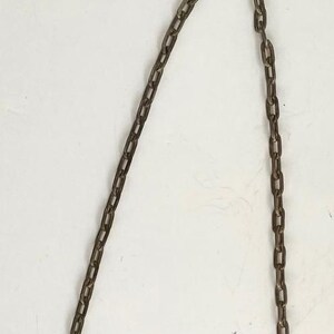 Peut inclure: Gros plan d'une cha&icirc;ne m&eacute;tallique &agrave; la finition sombre et vieillie. La cha&icirc;ne est suspendue sur un fond blanc, avec les maillons clairement visibles. La cha&icirc;ne est probablement utilis&eacute;e &agrave; des fins d&eacute;coratives ou fonctionnelles.