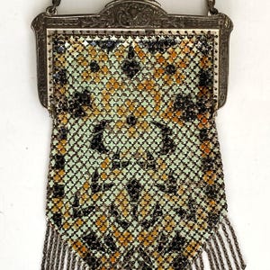 Peut inclure: Un sac &agrave; main ancien en m&eacute;tal maill&eacute; avec un cadre d&eacute;coratif et une cha&icirc;ne. Le sac pr&eacute;sente un motif g&eacute;om&eacute;trique noir, or et vert, avec une frange de cha&icirc;ne en bas. Le cadre est orn&eacute; d'une fermeture &agrave; fermoir.