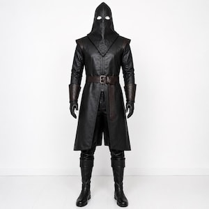May include: A full-body black leather costume featuring a hooded mask with eye cutouts, a long coat with structured shoulders, dark brown cuffs, and a matching brown belt with a silver buckle. The outfit includes black trousers and tall boots.