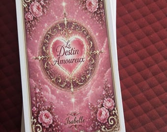May include: A rectangular tarot card with a pink background featuring floral accents, a central heart-shaped emblem, and the text Le Destin Amoureux and Isabelle. The card has an ornate gold-toned border and a soft, glowing light effect.