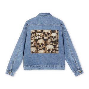 Può includere: Una giacca in denim azzurro con una grande stampa grafica rettangolare sul retro. La stampa mostra una collezione densa e sovrapposta di teschi umani color beige con orbite e cavità nasali scure, che copre il centro del pannello posteriore.