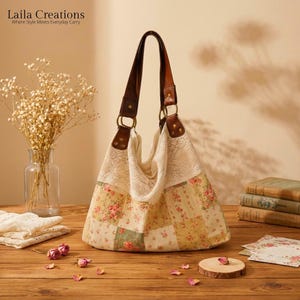 May include: A hobo-style handbag featuring a patchwork floral fabric body in shades of pink, green, and yellow, accented with a cream-coloured lace upper panel and brown leather shoulder straps attached with gold-tone metal rings and rivets.