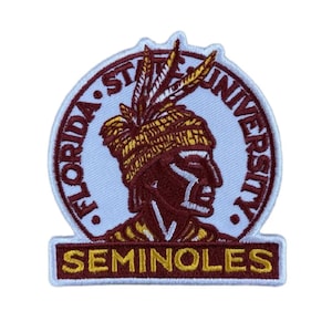 May include: A circular embroidered patch featuring the Florida State University logo in garnet and gold thread on a white background. The design depicts a profile of a figure wearing a feathered headdress, with the text SEMINOLES in a rectangular base.