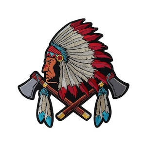 May include: An embroidered patch featuring a profile of a person wearing a large feathered headdress in red, white, and blue, positioned above two crossed grey-headed tomahawks with brown handles and dangling feathers in blue and white.